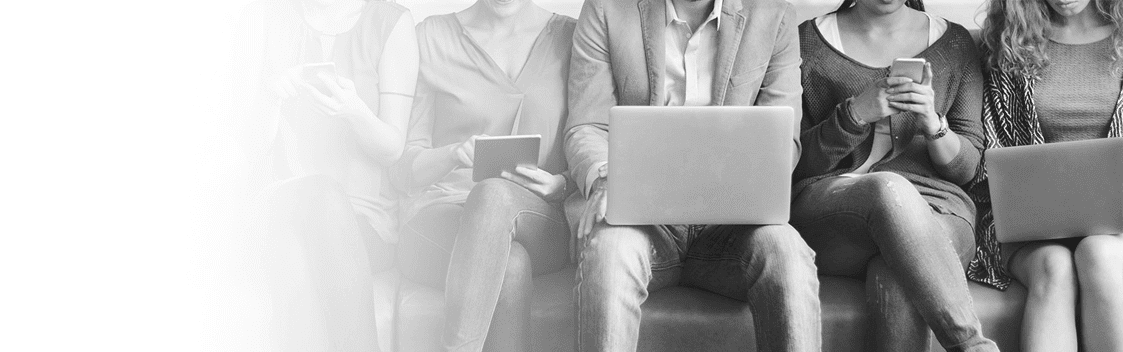 People Sat On Sofa Using Electronics