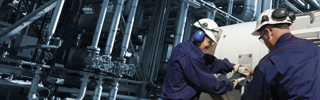 Two Men in Hard Hats Inspecting Tank