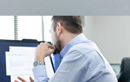 Man Sat On Phone at Computer